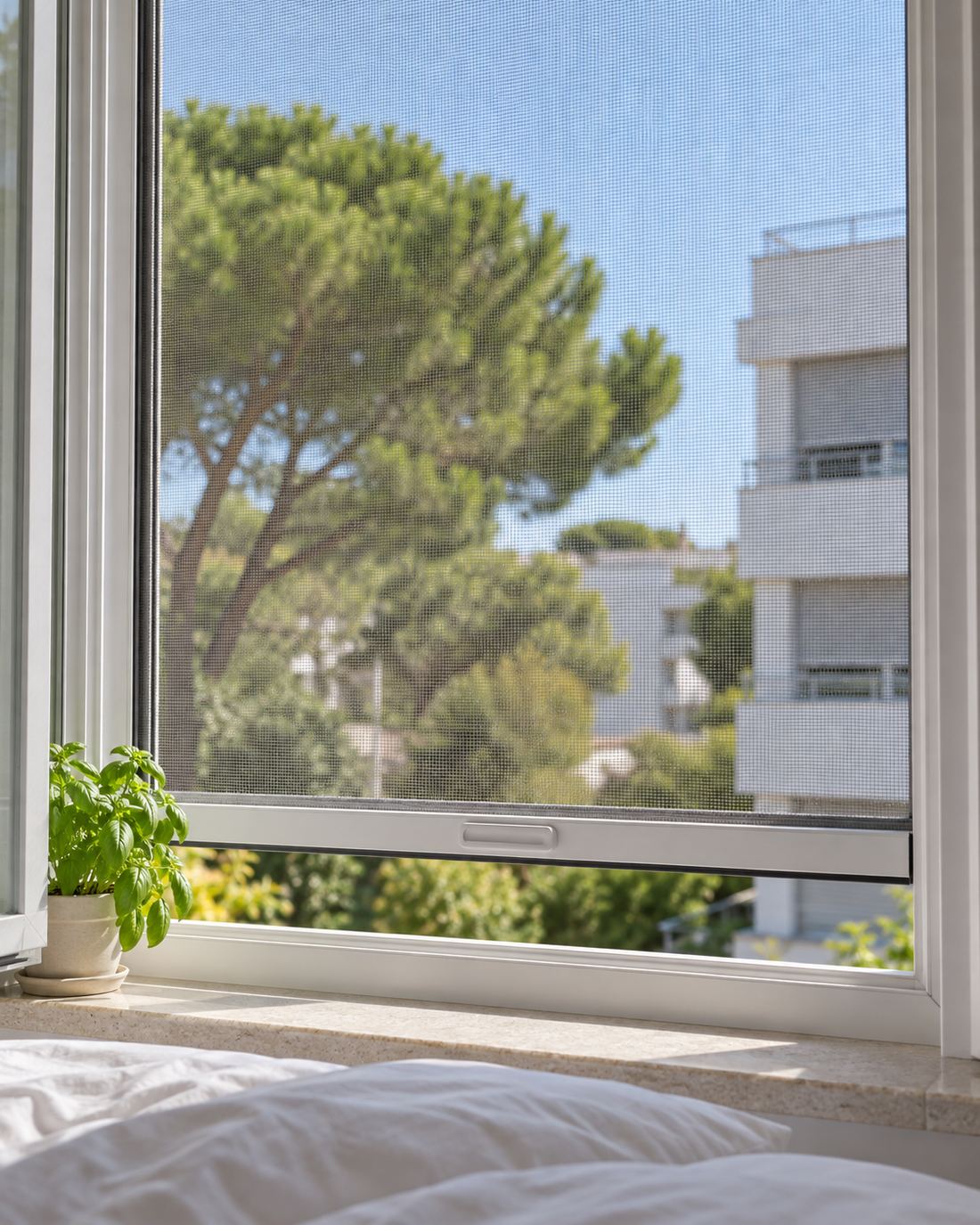Ventana de dormitorio abierta con mosquitera enrollable bajada en pleno verano